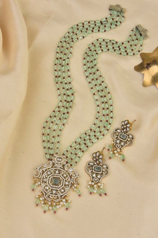 A traditional jewelry set featuring a multi-strand beaded necklace with a large, ornate pendant and matching earrings. The necklace and earrings are adorned with intricate designs and embellishments.