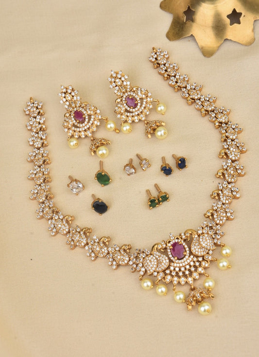 A set of gold jewelry featuring a necklace, a pair of earrings, and multiple pairs of stud earrings. The necklace and earrings are adorned with intricate designs, pearls, and gemstones.