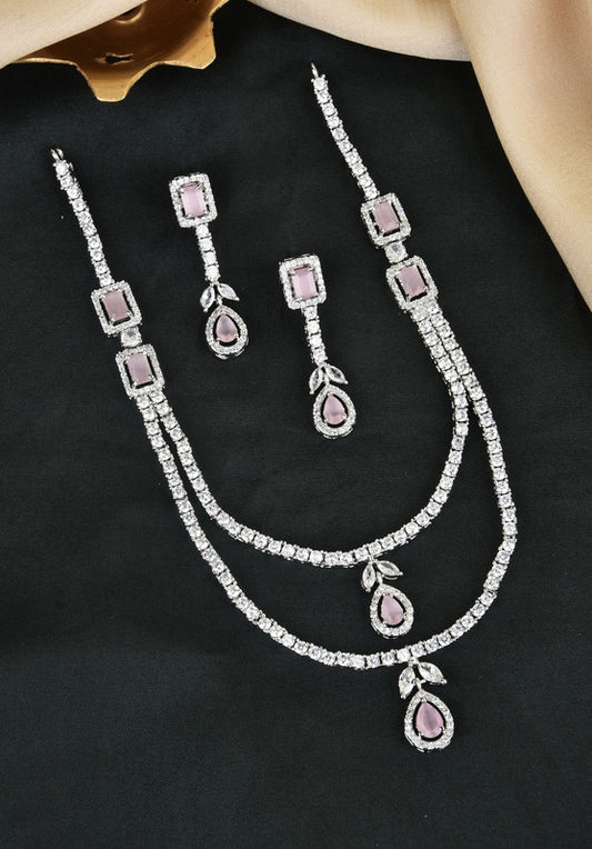 A set of silver jewelry with pink gemstones, including a necklace and matching earrings, displayed on a black surface.