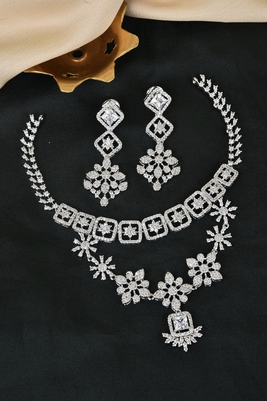 A set of silver jewelry consisting of a necklace, a pair of earrings, and a bracelet, all adorned with intricate floral and geometric designs.