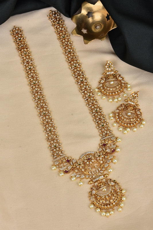 A gold necklace with intricate designs and matching earrings, adorned with pearls and gemstones.