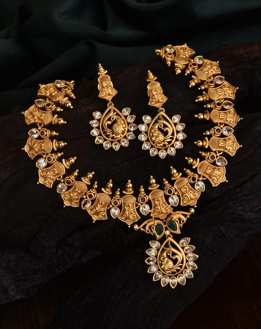 Gold necklace and earrings set with intricate designs and embedded gemstones.