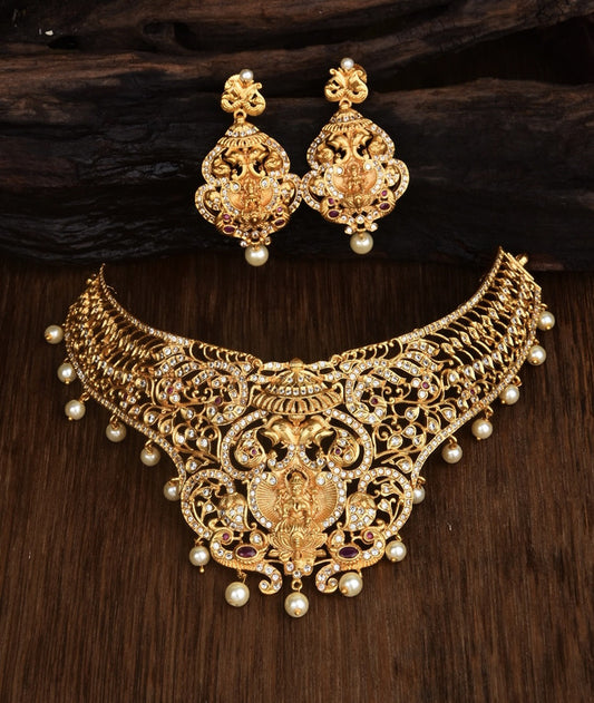 A set of ornate gold jewelry consisting of a choker necklace and matching earrings, adorned with intricate designs, pearls, and gemstones.