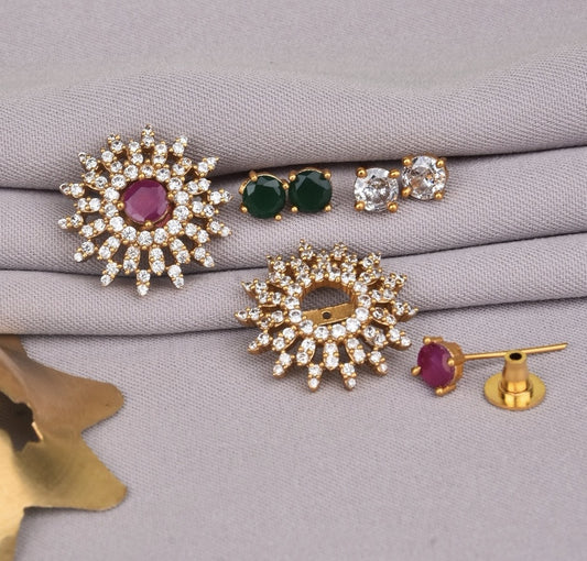 A set of gold earrings with various designs, including a pair with a central red stone surrounded by clear stones, a pair with green stones, and a pair with clear stones.