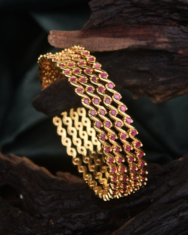 A gold bracelet with intricate red gemstone detailing.