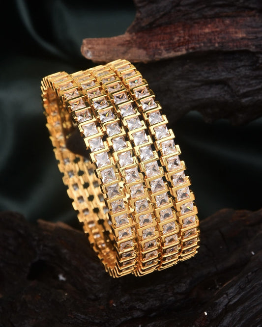 Three gold bangles with square-cut clear stones arranged in a grid pattern.