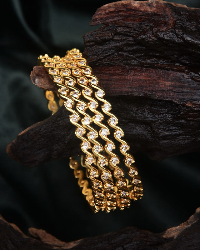 Gold bangles with intricate designs and embedded gemstones.