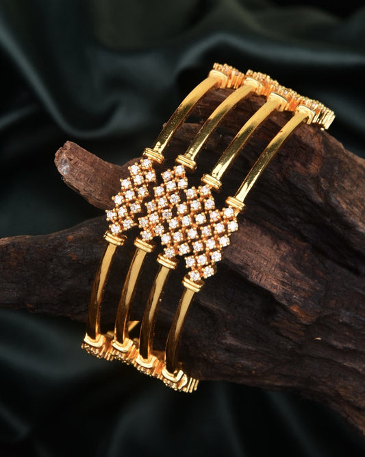 Four gold bangles with intricate diamond-studded designs.