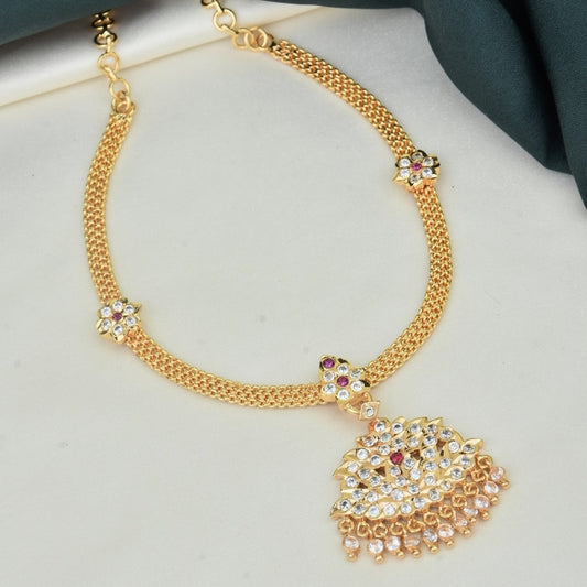 A gold necklace with a decorative pendant featuring intricate designs and embedded gemstones.