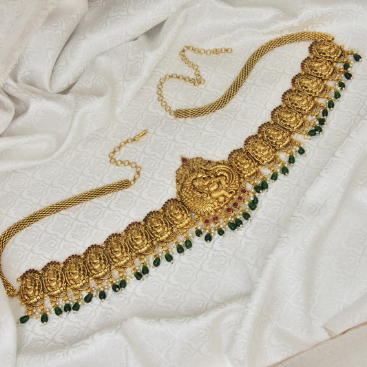 Gold waist belt with intricate designs and green bead accents.