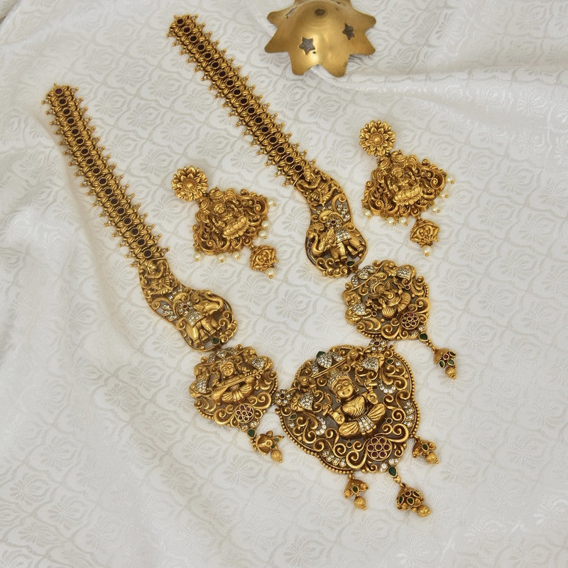 Gold temple jewelry set with intricate designs, including two long necklaces, a pair of earrings, and a pendant.