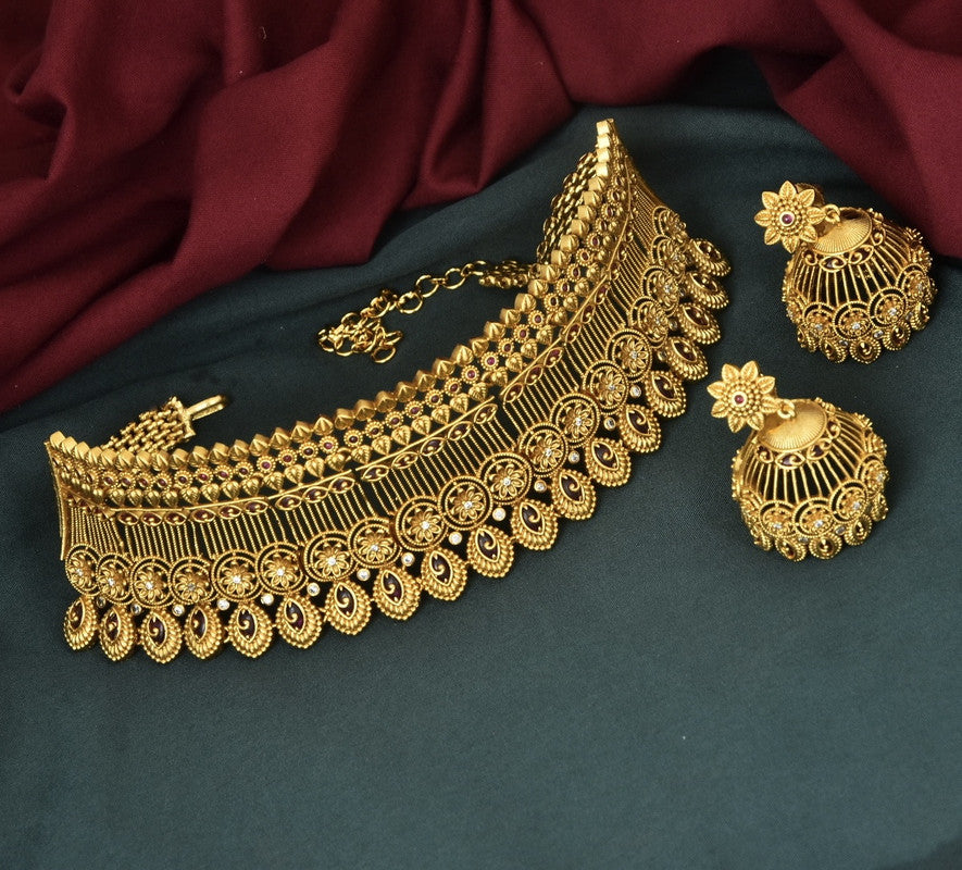 A gold choker necklace with intricate designs and matching earrings.
