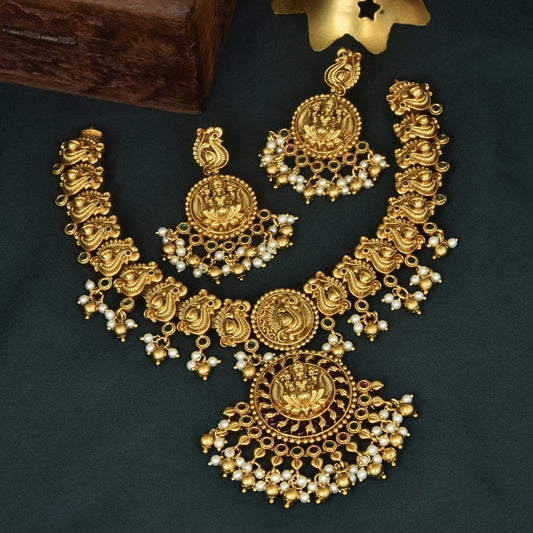 Gold necklace and earrings set with intricate designs and pearl accents.