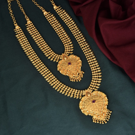 Gold layered necklace with intricate designs and red gemstone accents.