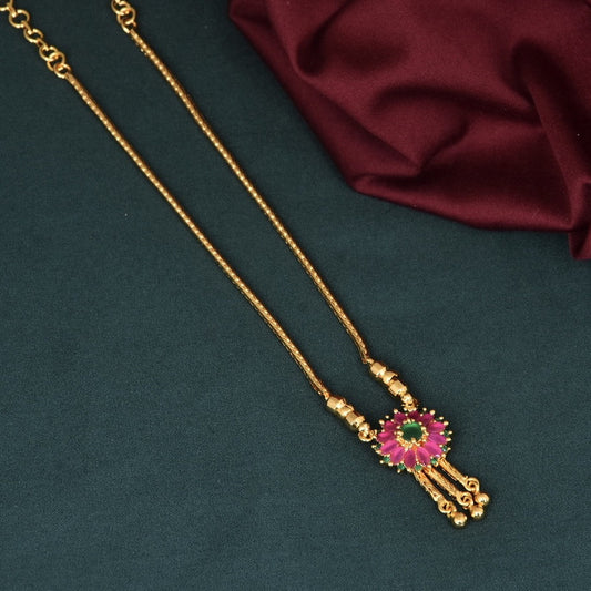 Gold necklace with a pink and green pendant.