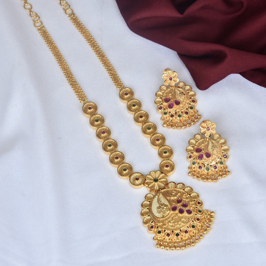 Gold necklace and matching earrings set with intricate designs and red gemstone accents.