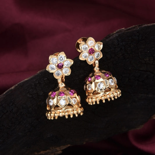 Gold jhumka earrings with floral design and embedded gemstones.