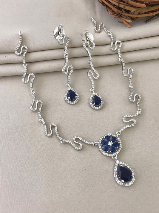 A silver necklace and earring set with blue gemstone accents.